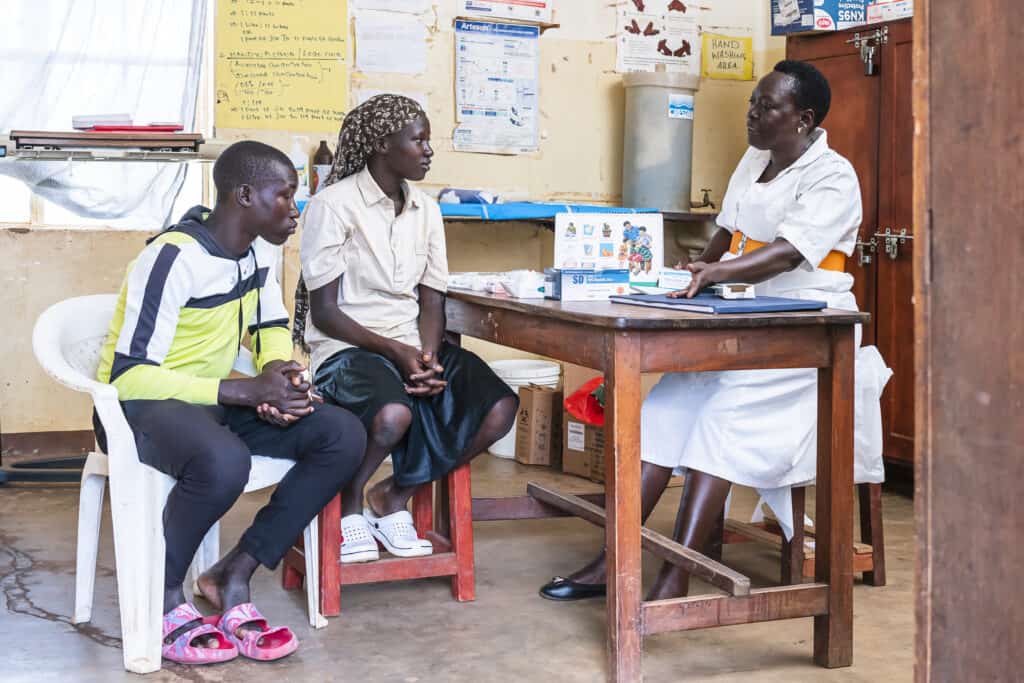 Two young people, a teenaged boy and girl, speak with an adult about family planning and reproductive health