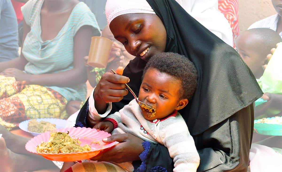 A mother feeds her child a nutrition meal.