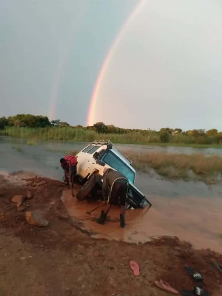 truck stuck in mud with rainbow in the background
