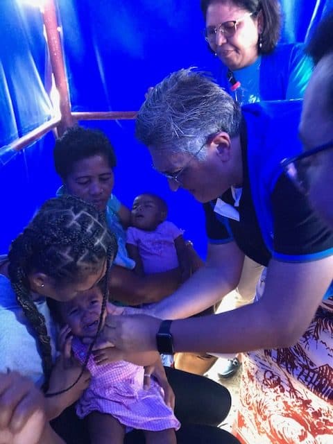 Enrique Paz helps administer a vaccine to a child.