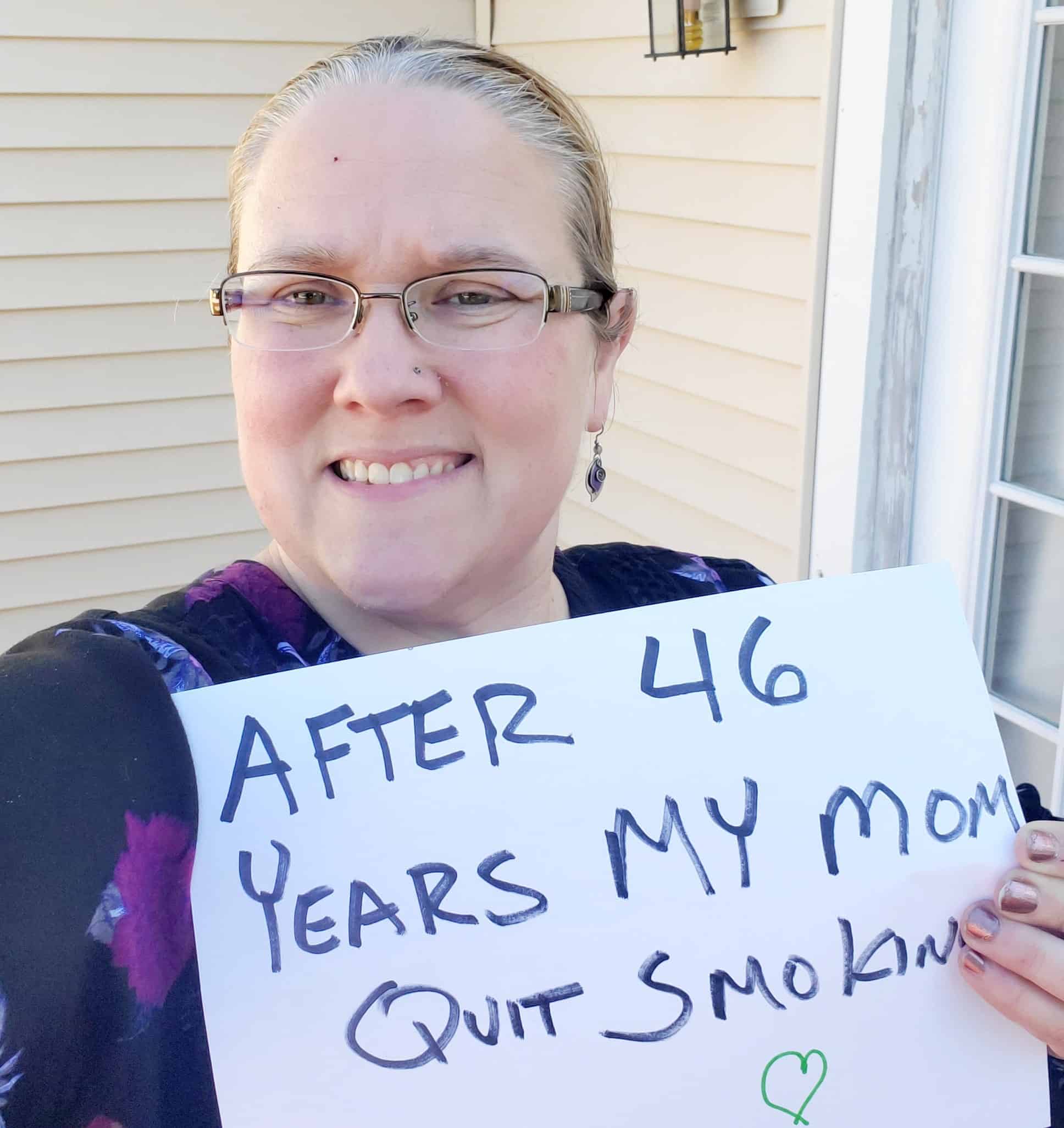 Jennifer Wall holds a sign that reads "after 46 years my mom quit smoking"