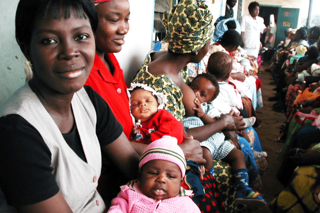 Nigerian mothers hold their young babies while they sit waiting to be attended to at a community clinic run by JSI.