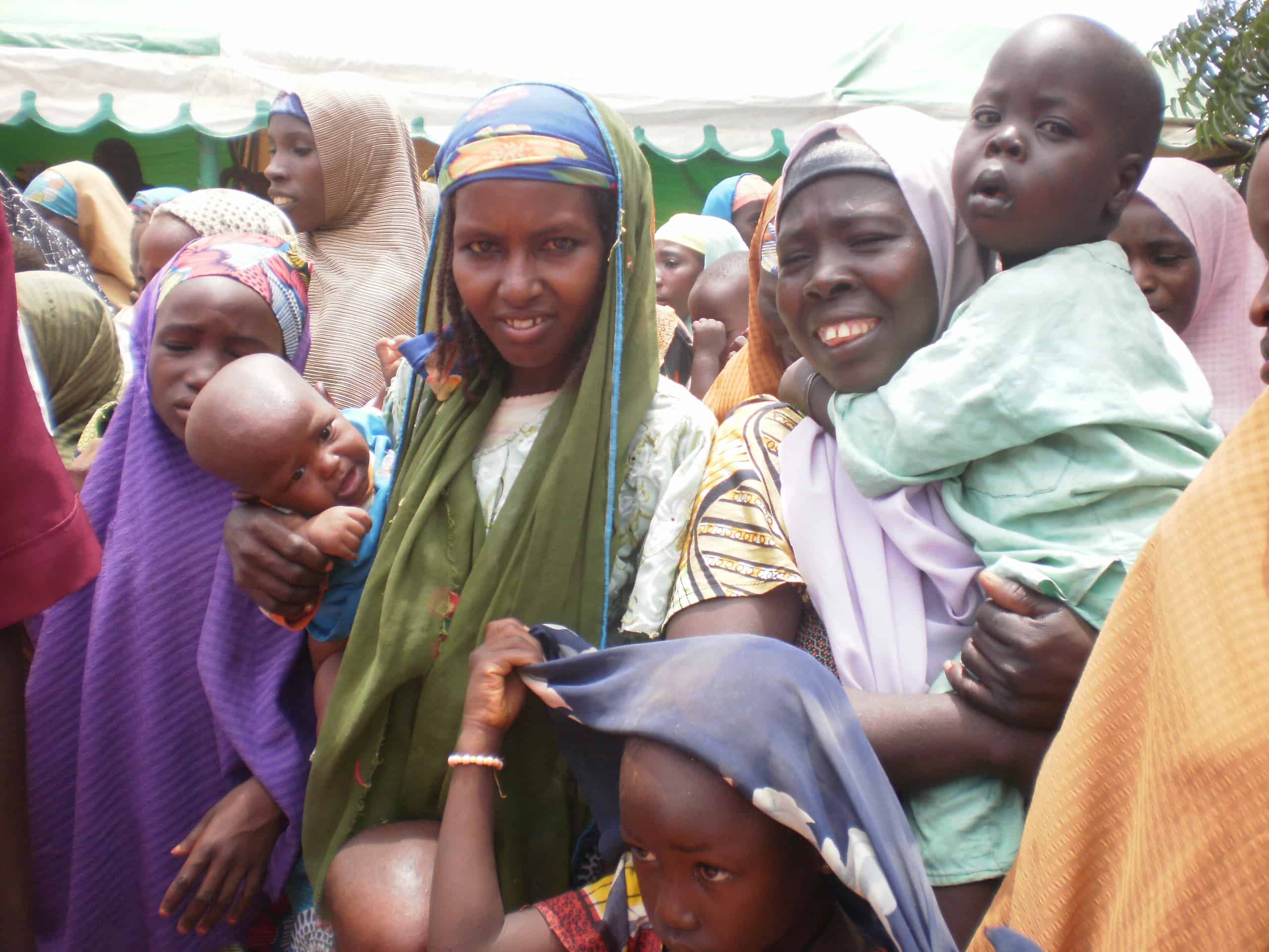 Nigerian mothers hold their children while attending an event held by JSI's Targeted States High Impact Project in Nigeria