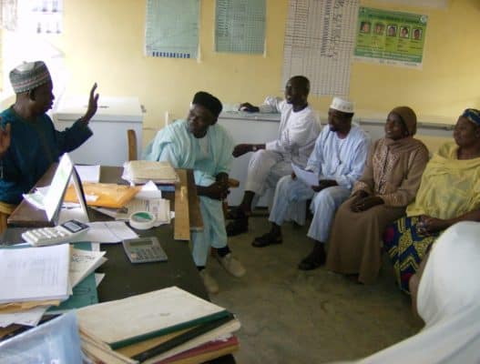A group of health workers sit and discuss in Nigeria.