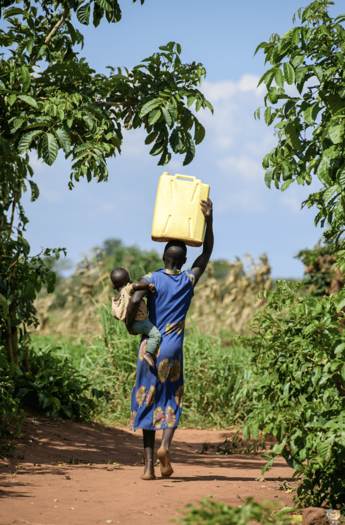 Sandra walks in her village in Uganda while holding her son.