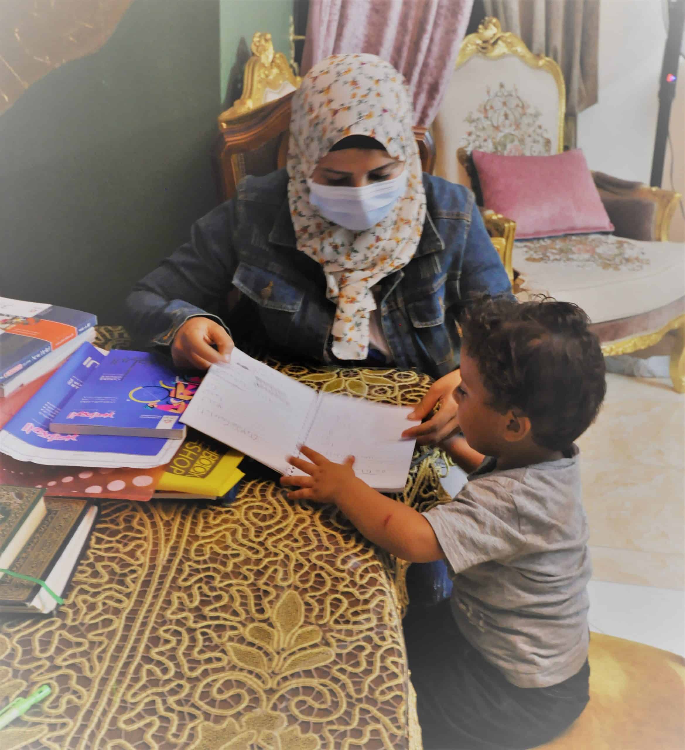 Wafaa helps her son with homework
