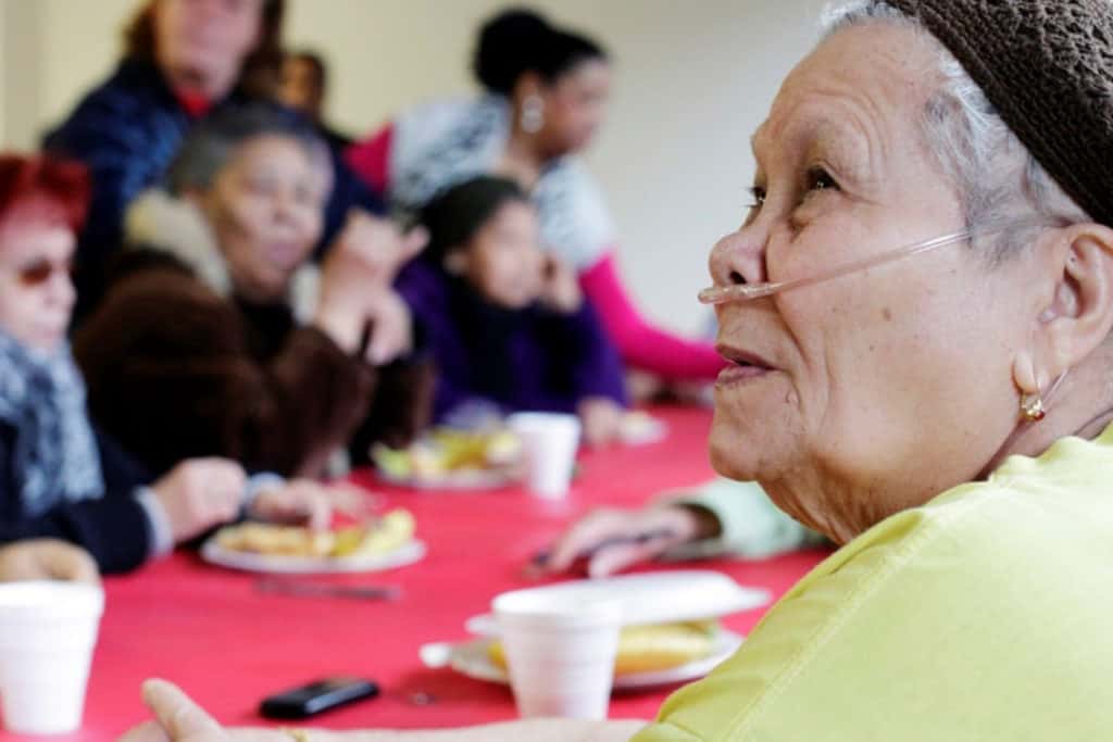 A woman sits at a table in a nursing home.