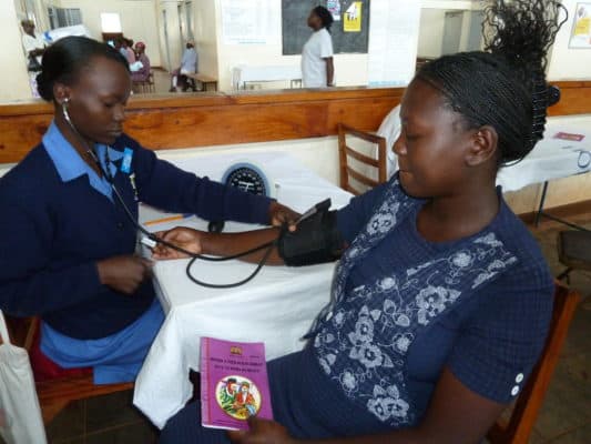 A health worker measures a women's pulse in a health center in Kenya