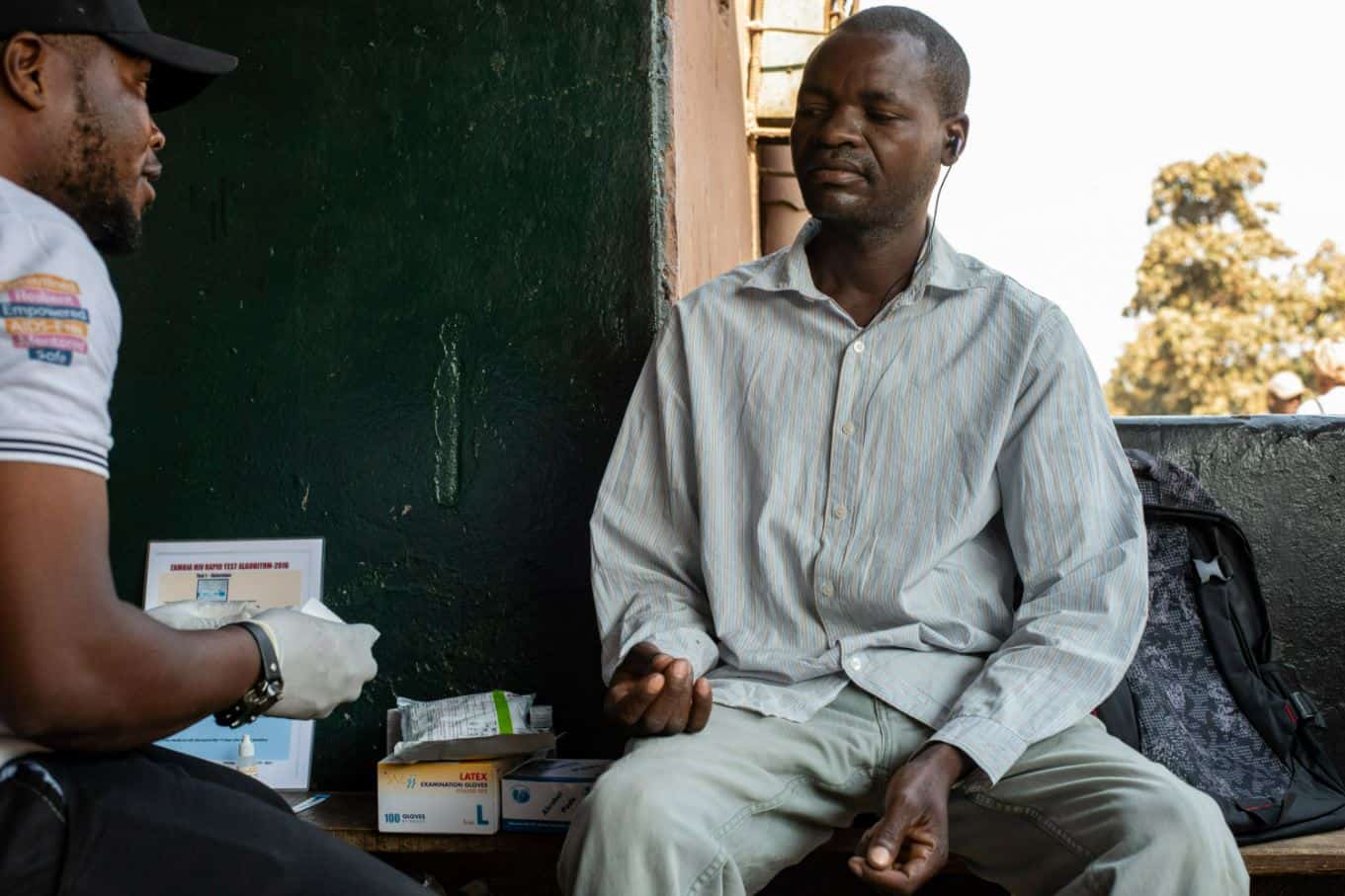 A Zambian man speaks with a health worker about condoms