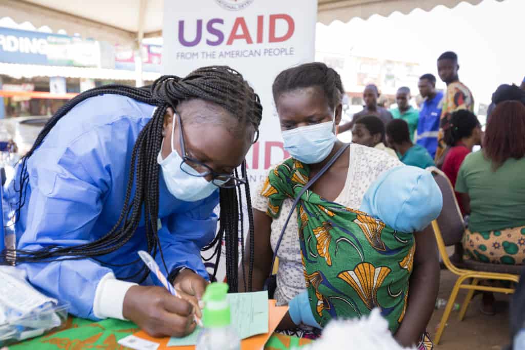 A breastfeeding mother receives her COVID-19 vaccine certificate after being vaccinated at a USAID DISCOVER-Health mobile site in Ndola.
