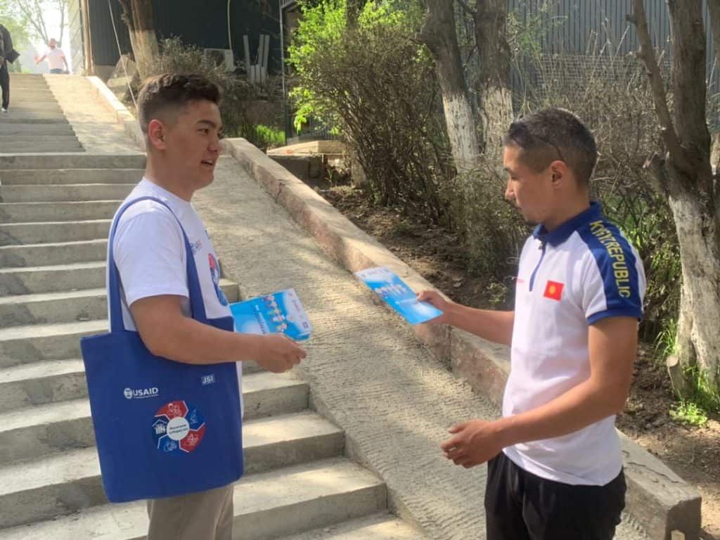 A young man passes out information on TB to another youth