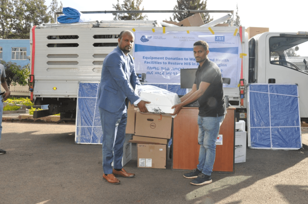 Two men carry a donated printer to a health facility in Ethiopia