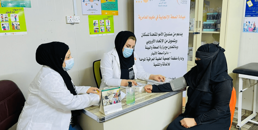 An iraqui woman gets her blood pressure checked by two female nurses