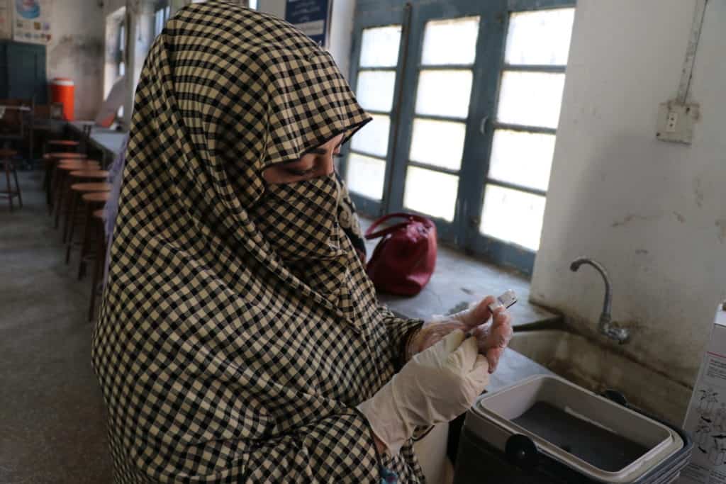 Pakistani woman examines a vaccine during the USAID IHSS-SD Activity conference in Peshawar, Pakistan