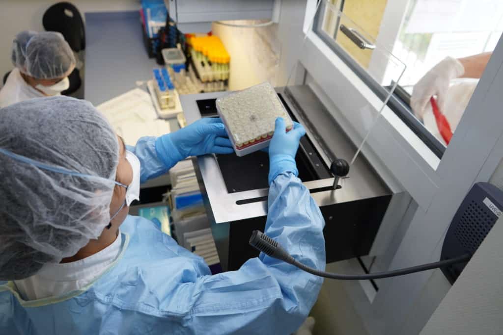 A lab worker examines samples in tubes.