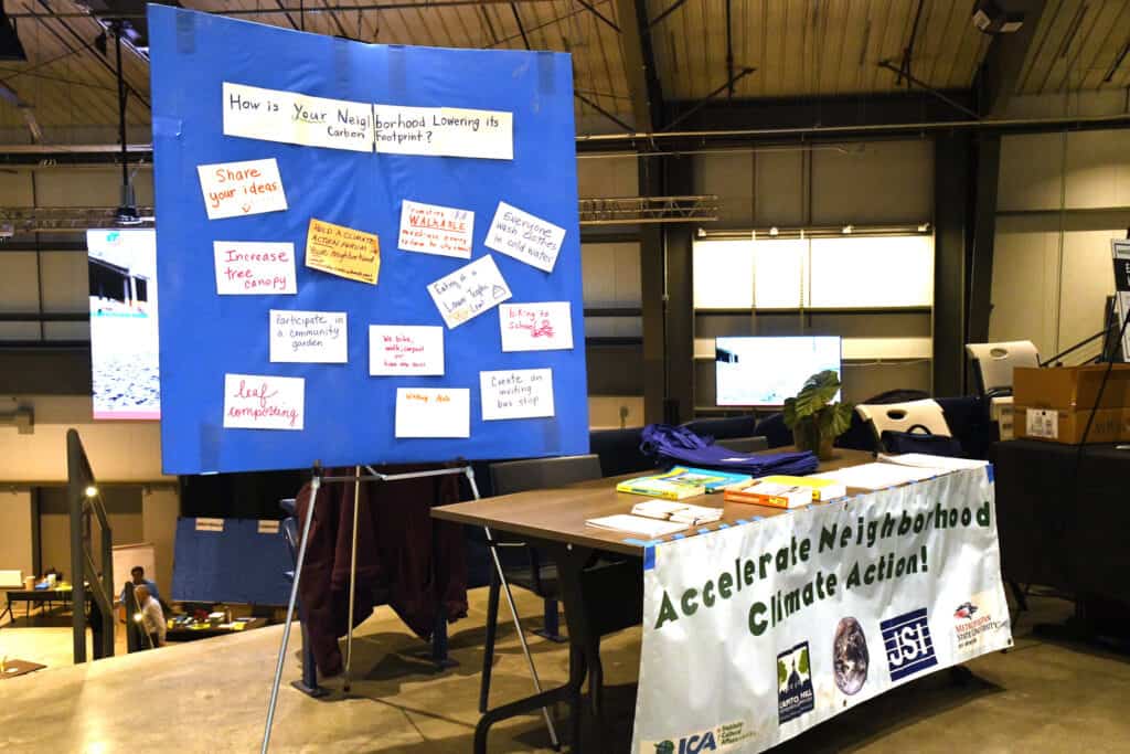 A presentation board with a table in front for Accelerate Neighborhood Climate Action