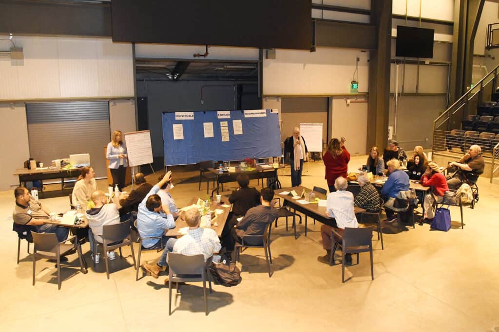 A group of people sit in chairs and look at information presented on a board