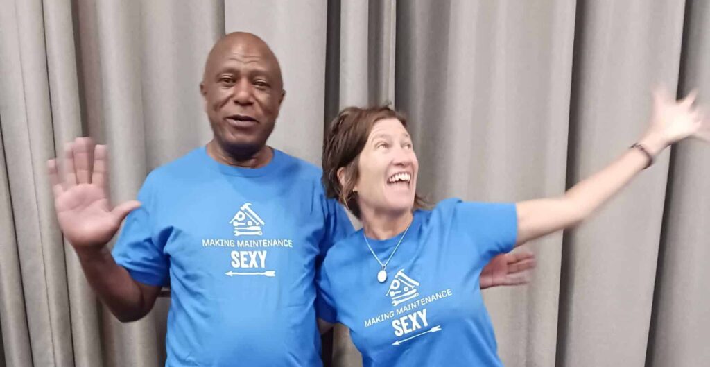 Amos Chweya and Wendy Prosser pose for a photo wearing matching blue shirts