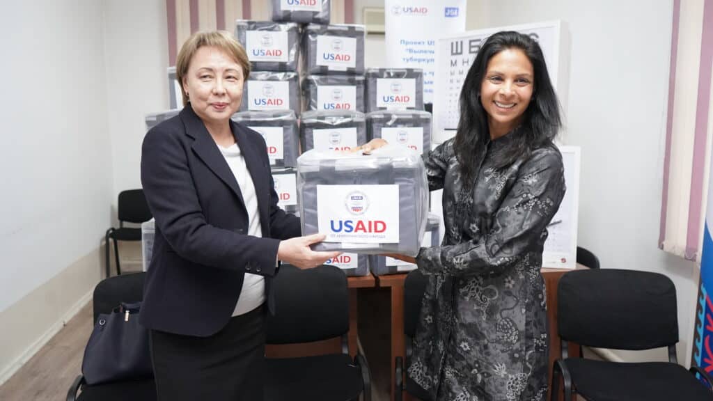 Two woman holding USAID donated medical equipment