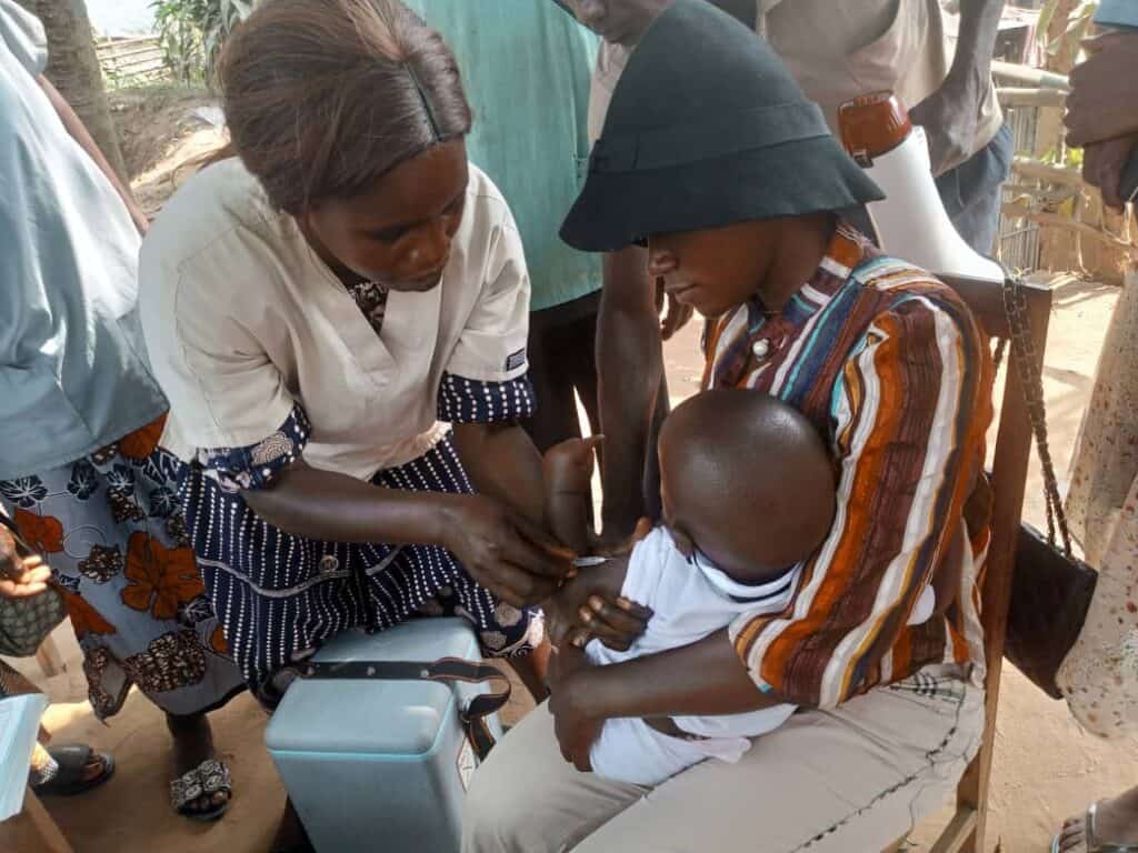 A mother holds a child that is getting a vaccination from a healthworker