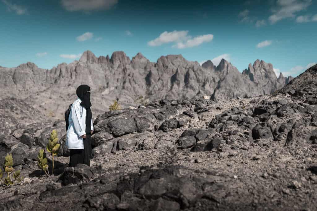 A woman walks across difficult terrain in Yemen