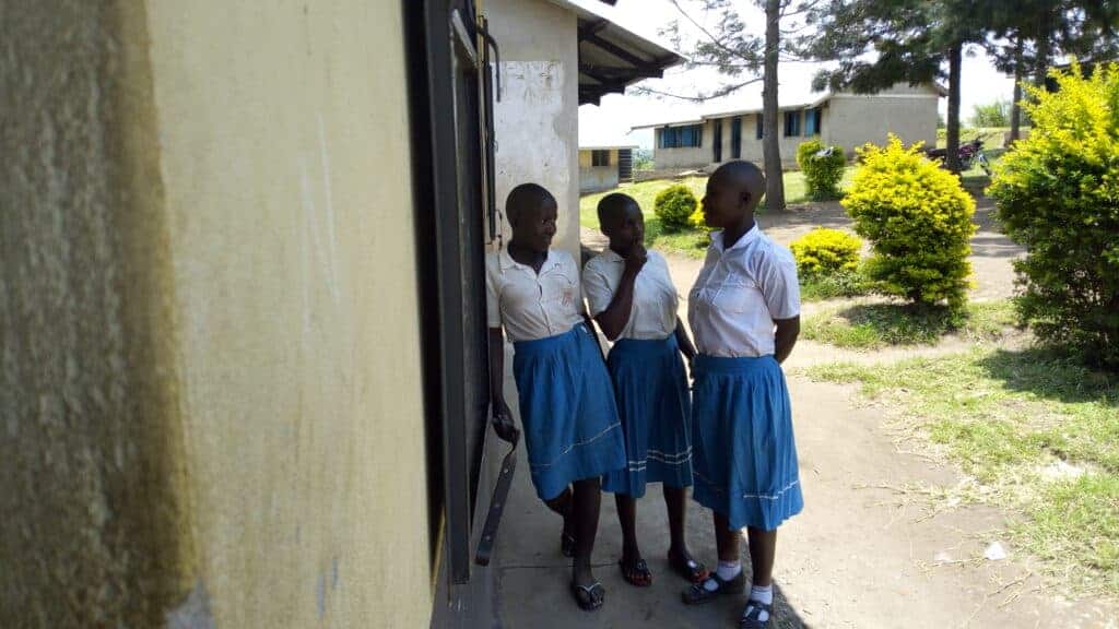 Three school girls talk outside a school in Africa