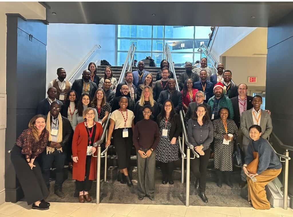 A large group of people pose together for a photo representing the JSI delegation at GDHF 2023, representing 10 JSI projects from 18 supported countries.