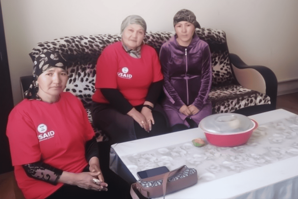 Three women who are community health volunteers sit posing for a photo.