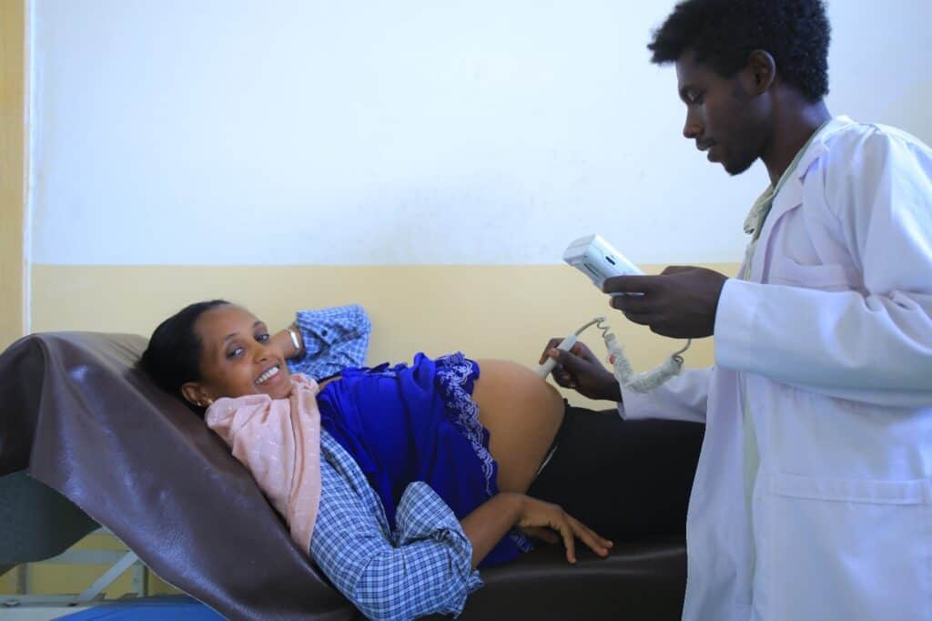A pregnant Ethiopian woman receives an ultrasound by a male health care provider.